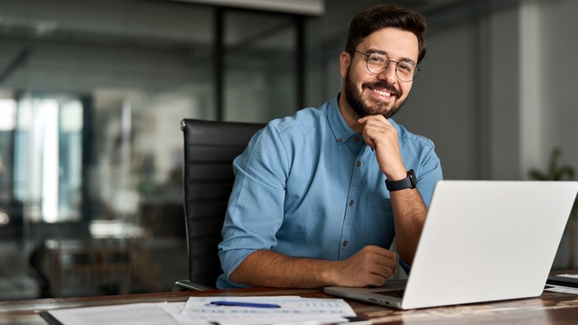 retrato de un empresario feliz sentado frente a su ordenador port&aacute;til