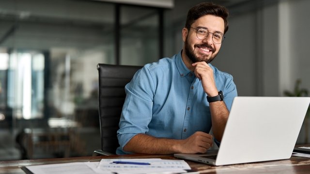 retrato de un empresario feliz sentado frente a su ordenador portátil