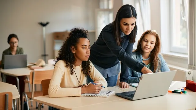 profesora de ELE y estudiantes usando un ordenador portátil durante la clase de español