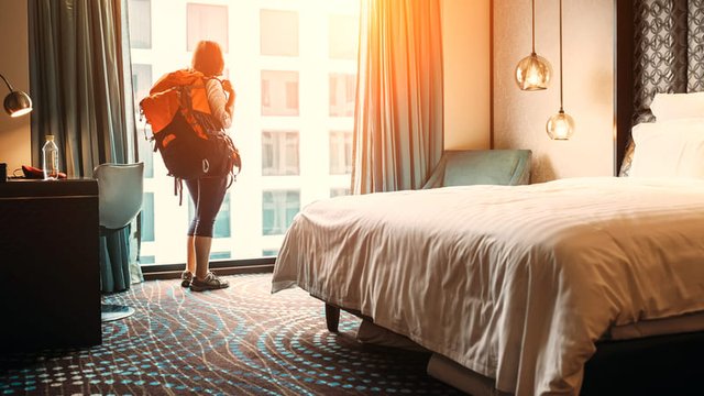 mujer que viaja con mochila se aloja en habitación de un hotel